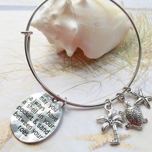 May include: Silver charm bracelet with a charm that reads "may you always have a shell in your pocket & sand between your toes". The bracelet also has charms of a palm tree, a turtle, and a starfish.