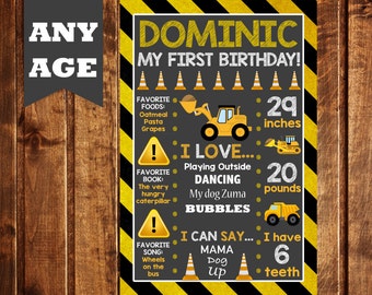 May include: A black and yellow construction-themed first birthday sign for a boy named Dominic. The sign includes details about his favorite foods, book, activities, and a photo of him with his age and measurements. It says "Dominic My First Birthday!" at the top.