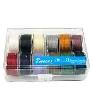May include: A clear plastic case containing a set of sewing machine bobbins. The bobbins are wound with various colors of thread, including white, black, gray, and shades of red, blue, and green. The case has a label that reads "One-G".