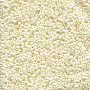 May include: Close-up of a pile of small, off-white, cylindrical beads. Each bead has a hole running through the center. The beads are scattered, creating a textured surface. The color is a creamy, pale ivory.