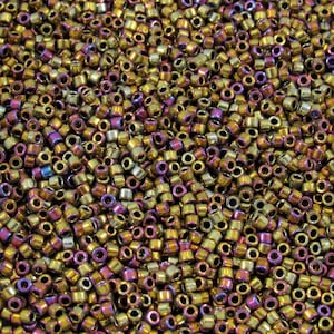 May include: A close-up shot of a pile of small, cylindrical beads. The beads have a metallic finish with a mix of gold, purple, and silver hues. They are densely packed together, creating a textured surface. These beads are suitable for jewelry making and crafts.