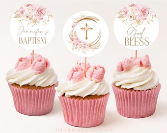 May include: Three pink and white cupcakes with gold and white toppers. The toppers feature a cross, a floral design, and the text "Jennifer's Baptism" and "God Bless".