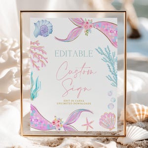 May include: A framed sign with a mermaid theme. The sign features watercolor illustrations of seashells, coral, and mermaid tails. The text on the sign reads "Editable Custom Sign" in a script font. The frame is gold.