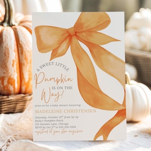 May include: A baby shower invitation featuring an orange watercolour bow and the words "A Sweet Little Pumpkin is on the Way!". The invitation provides details for Madeleine Christensen's baby shower, with pumpkins in the background.