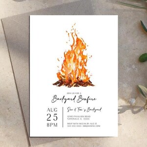 Bonfire party invitation template with a hand painted watercolor fire illustration and simple black party details. The design includes space for the date, time, backyard location and RSVP information. The printed invitation rests on a neutral stone surface with subtle greenery nearby. The natural setting complements a casual backyard bonfire, barbecue or outdoor party.