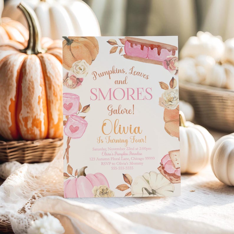 Editable Pumpkin Birthday Invitation standing upright on a rustic tabletop with a large heirloom pumpkin filling the left side of the scene and white pumpkins softly blurred in the background. Warm afternoon lighting creates a cozy harvest atmosphere that complements the watercolor smores, pink pumpkins, florals, and autumn leaves. Printable girls fall birthday invitation template.