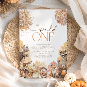 Könnte beinhalten: Eine rechteckige Einladungskarte mit dem Text "HE IS A wild ONE" in goldfarbenen Buchstaben. Die Karte zeigt Aquarellillustrationen von Waldtieren und Herbstlaub. Die Einladung ist für Alistairs ersten Geburtstag.