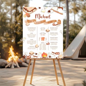 Puede incluir: Un póster personalizado de hitos del primer año sobre un caballete de madera. El póster presenta ilustraciones de acuarela de s'mores, una fogata y texto, incluido el nombre "Michael", altura 63.5 cm, y peso 6.8 kg.