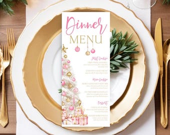 Könnte beinhalten: Eine festliche Menükarte mit einem Weihnachtsbaumdesign, mit rosa Ornamenten und Geschenken. Die Menükarte liegt auf einem goldumrandeten Teller, mit goldenem Besteck und einem Zweig Grün, wodurch eine festliche Tischdekoration entsteht.