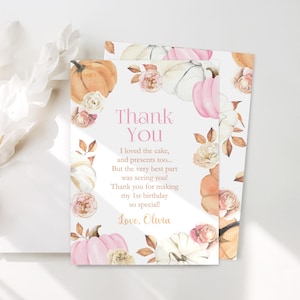 Editable thank you card for a pumpkin first birthday party featuring watercolor pink white and orange pumpkins soft roses and autumn leaves with personalized text for guests displayed on a white surface with subtle floral shadows perfect for coordinating with an autumn themed first birthday invitation set for girls