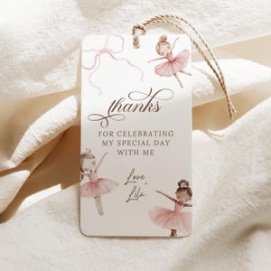 May include: A rectangular gift tag with a watercolor design featuring ballerinas in pink tutus. The tag includes the text "thanks for celebrating my special day with me" and "Love, Lila". A twine string is attached.