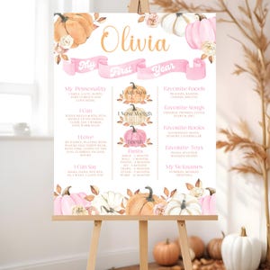 Editable pumpkin first birthday milestone board featuring pink white and orange pumpkins with soft roses and autumn leaves personalized with baby’s name stats favorite things and milestones displayed on an easel in a cozy fall themed room with pampas grass decor for a rustic and elegant autumn birthday celebration backdrop