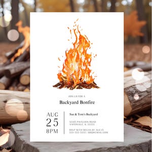 Backyard bonfire invitation featuring a large watercolor campfire with warm orange and golden flames. The clean white invitation includes modern black typography with the date, time, location and RSVP details. The invitation is displayed outdoors surrounded by stacked firewood and glowing firelight. A warm rustic setting highlights the cozy bonfire party theme.