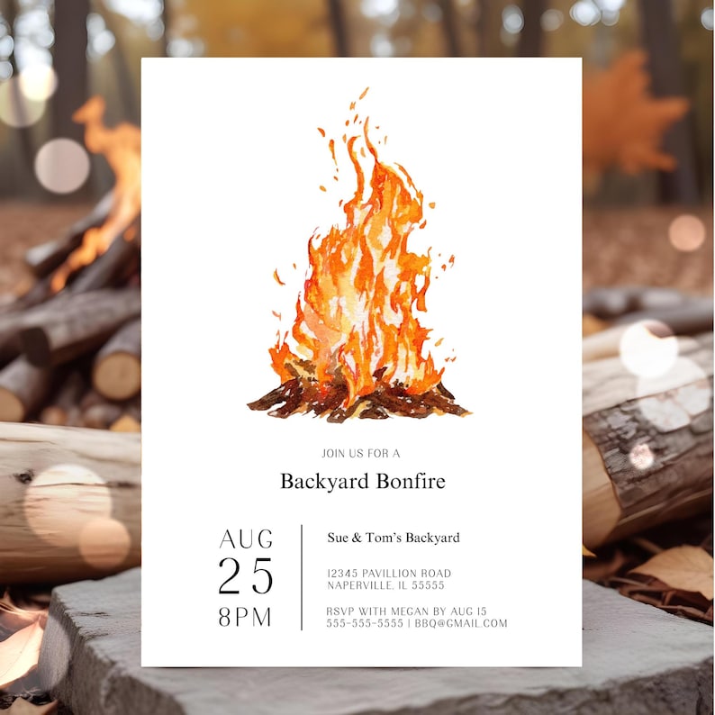Backyard bonfire invitation featuring a large watercolor campfire with warm orange and golden flames. The clean white invitation includes modern black typography with the date, time, location and RSVP details. The invitation is displayed outdoors surrounded by stacked firewood and glowing firelight. A warm rustic setting highlights the cozy bonfire party theme.