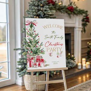 May include: A white rectangular sign on a wooden easel featuring a watercolor illustration of a Christmas tree with red ornaments and gifts. The text reads: WELCOME The Smith Family Christmas PARTY SATURDAY 20TH 2025 in gold, green, and red script.