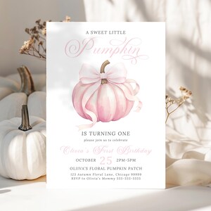 Op de afbeelding: Een roze en witte uitnodigingskaart met de tekst "A Sweet Little Pumpkin" en "Is Turning One". De kaart toont een aquarel illustratie van een roze pompoen met een strik. De kaart bevat ook de datum, tijd en locatie van het feest.
