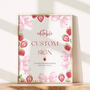 May include: A framed sign with a white background, adorned with watercolor illustrations of strawberries and pink bows. The sign reads "editable CUSTOM SIGN" in a red script font, with additional text below.
