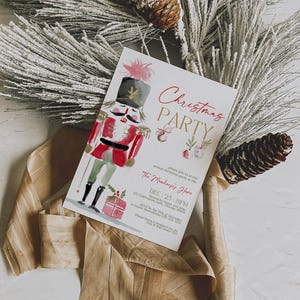 Watercolor Nutcracker Christmas Party Invitation template shown flat on a neutral background with frosted pine branches, pinecones, and ribbon. The elegant design includes red and gold lettering, painted ornaments, and gift illustrations, perfect for a holiday gathering or office Christmas celebration.