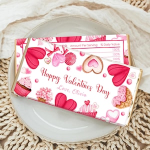 May include: Two Valentine's Day chocolate bars with pink and red watercolor illustrations of hearts, cupcakes, and candies. The bars are decorated with the text "Happy Valentines Day, Love, Olivia."