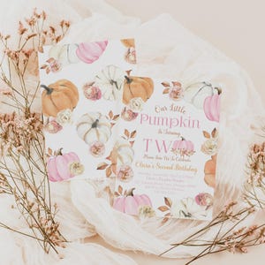Our Little Pumpkin second birthday invitation editable in Canva, featuring watercolor pumpkins, roses, and autumn leaves in soft pink, cream, and orange. Customizable wording celebrates a two-year-old’s birthday. Mockup shown with both front and back of the invitation against blush pink fabric and dried floral accents, styled for a romantic fall look.