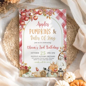 Könnte beinhalten: Eine herbstliche Einladungskarte mit dem Text "Apples, Pumpkins & Bales Of Hay" und "Olivia's 2nd Birthday." Das Design zeigt Aquarellillustrationen von Äpfeln, Kürbissen, Heuballen und einem rot-weiß karierten Muster. Die Karte befindet sich vor einem gewebten Hintergrund.