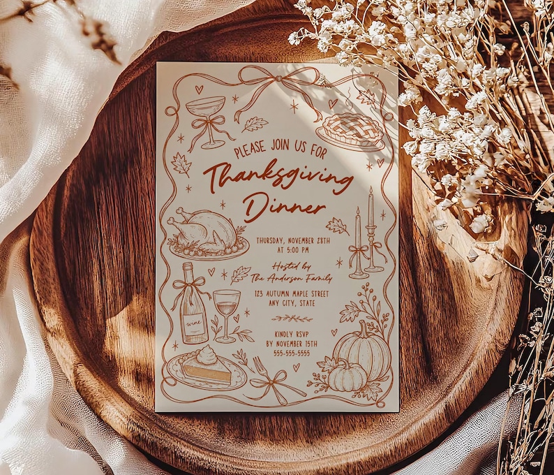 Thanksgiving dinner party invitation displayed on a rich wood serving board surrounded by soft cream fabric and dried flowers. The cream invitation features warm brown hand drawn turkey, pie, pumpkin, wine, candle and autumn leaf illustrations. Sunlight creates soft shadows across the card. The styling gives the Friendsgiving or Thanksgiving invitation a warm seasonal presentation.