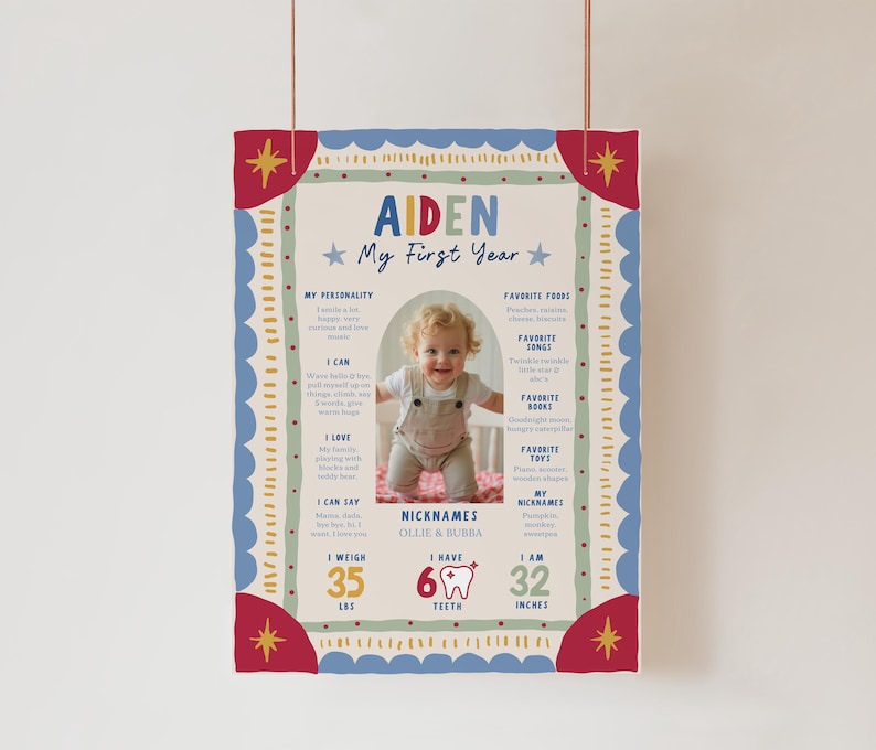 May include: A rectangular milestone poster titled Aiden My First Year with a central photo of a baby. The design features red, blue, and green borders with stars. Text includes personality, favorite foods, songs, books, toys, 35 lbs, 6 teeth, and 32 inches.