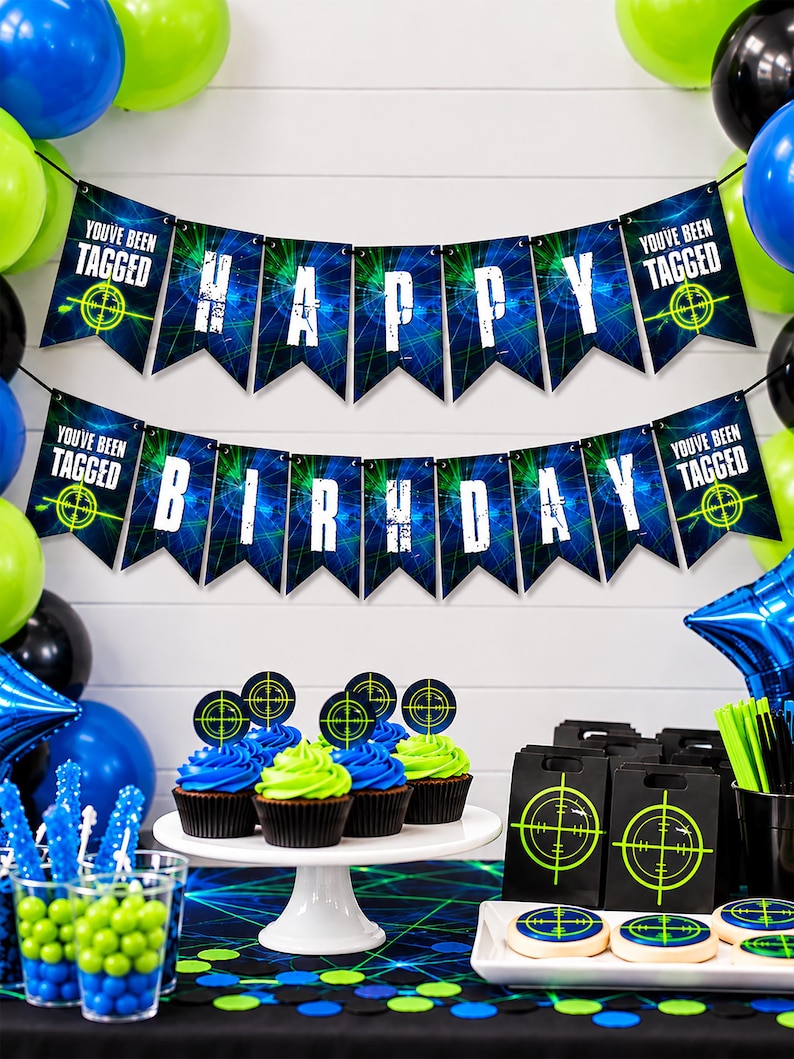 Printable laser tag bunting hangs across a white party backdrop surrounded by blue, lime green and black balloons. Two rows of 5x7" Happy Birthday pennants feature electric laser graphics and bold white gamer lettering, with You've Been Tagged target signs at each end. Coordinating cupcakes, favors and party treats are displayed below. The bright design creates a fun gamer and glow party setting.