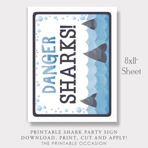 K&ouml;nnte beinhalten: Druckbarer Schild f&uuml;r eine Hai-Party. Das Schild ist blau und wei&szlig; mit einem Aquarell-Effekt. Es steht "Gefahr Haie!" und hat einen Rand aus blauen Blasen. Das Schild ist 20,32 cm x 27,94 cm gro&szlig;.