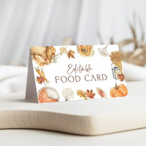 May include: A folded white card with the text "Editable FOOD CARD" surrounded by watercolor illustrations of fall harvest elements. The illustrations include a roasted turkey, pumpkins, and autumn leaves.