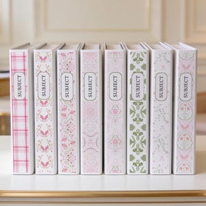 May include: Eight white binders standing in a row, each featuring a unique decorative pattern in shades of pink, green, and grey. Every binder spine includes a central rectangular label frame containing the word SUBJECT printed in black text.