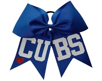May include: A royal blue cheer bow with white glitter lettering that says "CUBS" and a red glitter heart.