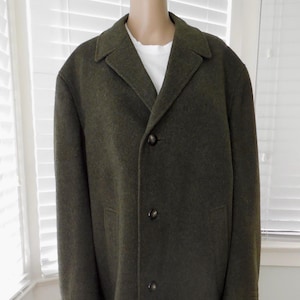 May include: A dark olive green wool coat with a classic design. The coat features a notched collar, three buttons, and two front pockets. The coat is knee-length and has a single vent in the back.