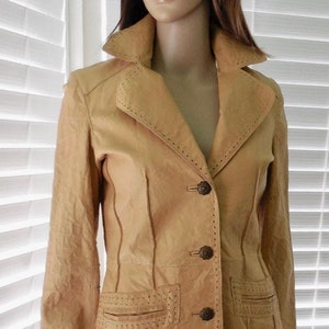 May include: A tan leather jacket with decorative stitching and three buttons. The jacket has a collar and long sleeves.