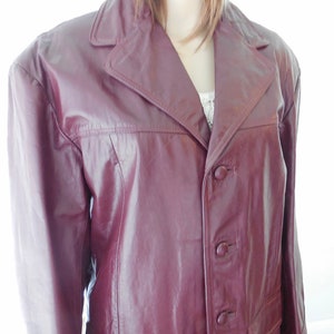 May include: A burgundy leather jacket with a button closure and a single pocket on the front.