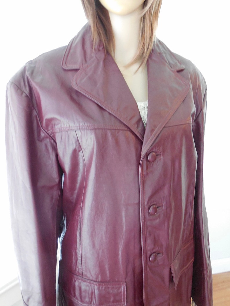 May include: A burgundy leather jacket with a button closure and a single pocket on the front.
