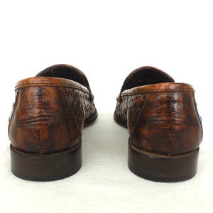 May include: A pair of brown leather loafers with a woven pattern. The loafers have a dark brown sole and a slightly pointed toe.