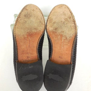 May include: A pair of black woven leather loafers with leather soles. The size is marked 7 1/2 on the soles.