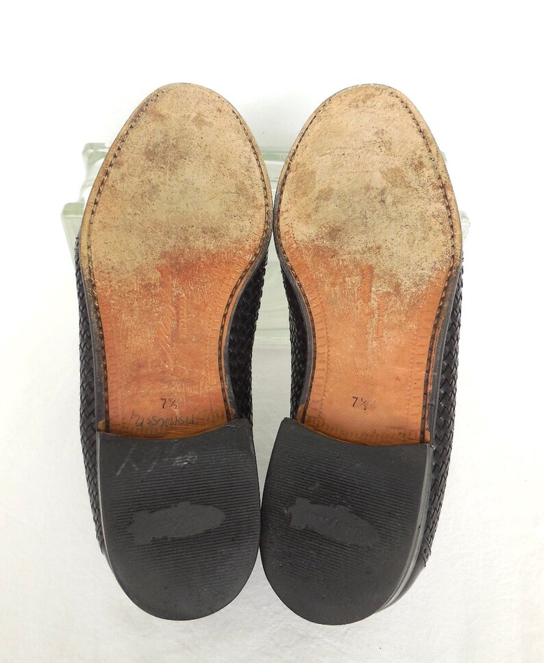 May include: A pair of black woven leather loafers with leather soles. The size is marked 7 1/2 on the soles.