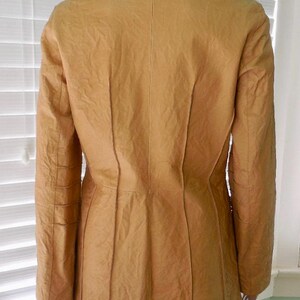 May include: A mustard yellow leather jacket with a fitted silhouette and a notched collar. The jacket has a textured surface and a single-breasted closure.