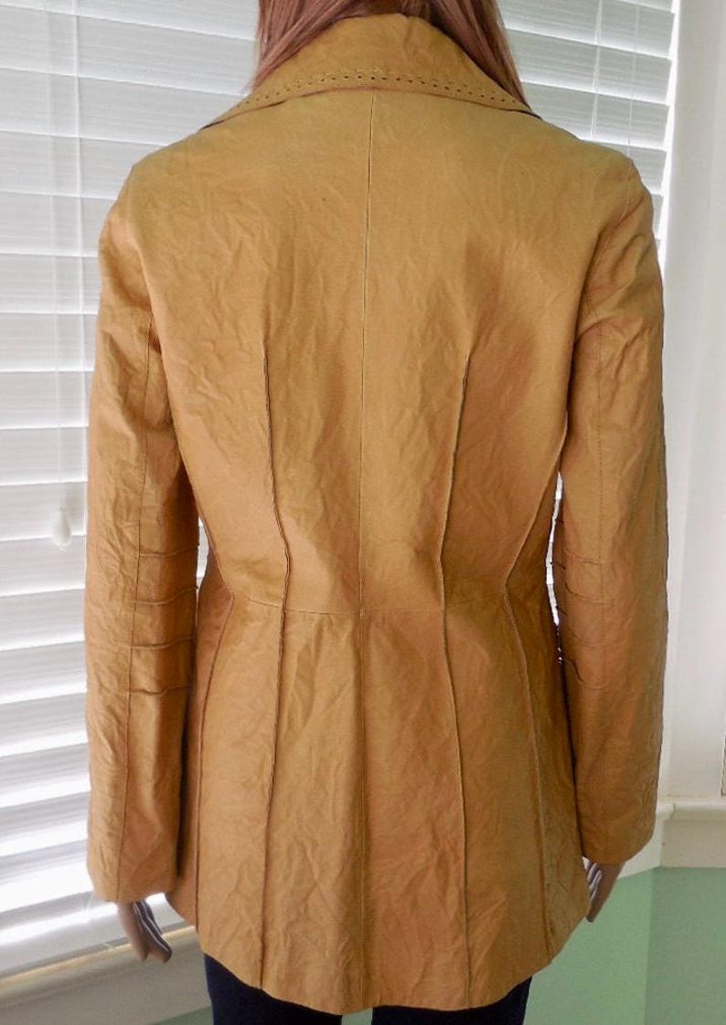 May include: A mustard yellow leather jacket with a fitted silhouette and a notched collar. The jacket has a textured surface and a single-breasted closure.