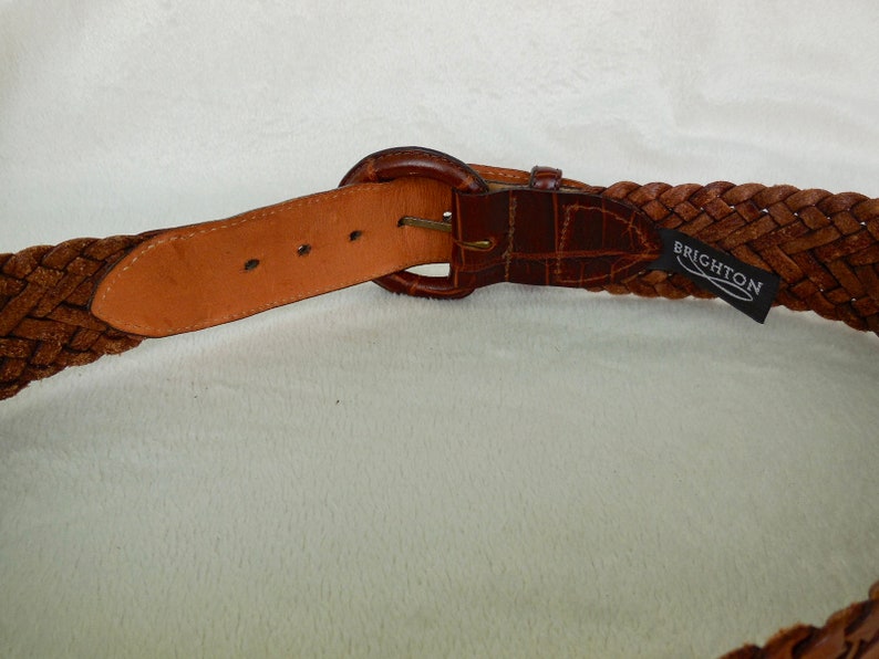 May include: A brown leather braided belt with a silver buckle and a Brighton brand label.