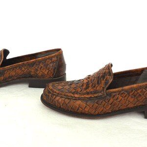 May include: A pair of brown leather loafers with a woven pattern. The loafers have a pointed toe and a low heel.
