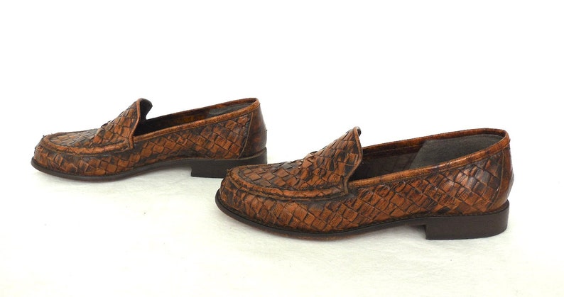 May include: A pair of brown leather loafers with a woven pattern. The loafers have a pointed toe and a low heel.
