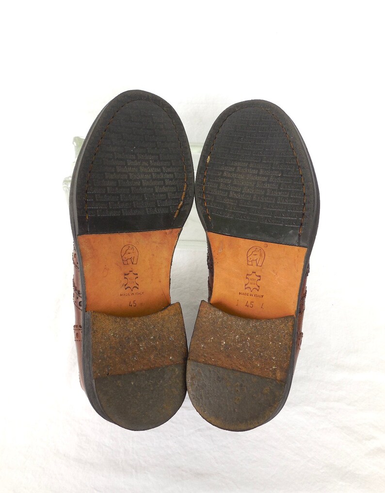 Pode incluir: Um par de sapatos de couro marrom com design brogue. Os sapatos t&ecirc;m uma sola de couro preto e s&atilde;o tamanho 45. Os sapatos s&atilde;o feitos na It&aacute;lia.
