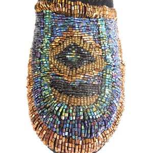 K&ouml;nnte beinhalten: Nahaufnahme einer schwarzen, mit Perlen besetzten Mokassinspitze. Die Spitze ist mit einem Muster aus schillernden Perlen in Gold-, Blau-, Gr&uuml;n- und Lilat&ouml;nen bedeckt. Die Oberseite des Mokassins ist aus schwarzem Wildleder.