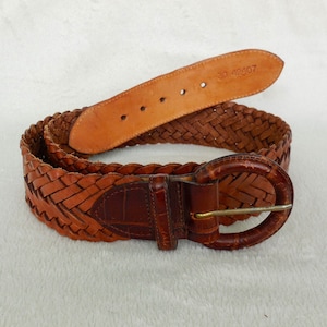 May include: A brown leather belt with a braided design and a round metal buckle. The belt has the number "30 42107" stamped on the back.
