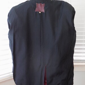 May include: A black leather jacket with a burgundy leather collar and a brown leather patch on the back. The jacket has a center back vent.