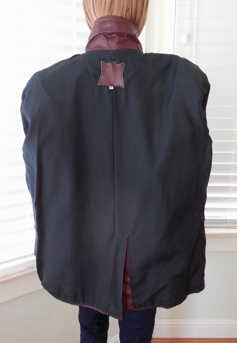 May include: A black leather jacket with a burgundy leather collar and a brown leather patch on the back. The jacket has a center back vent.
