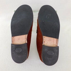 May include: A pair of brown loafers with textured uppers and black rubber outsoles. The soles feature a Vibram logo, a tan leather heel section with the number 9 stamped on it, and a black heel cap with an oval logo and small circular indentations.